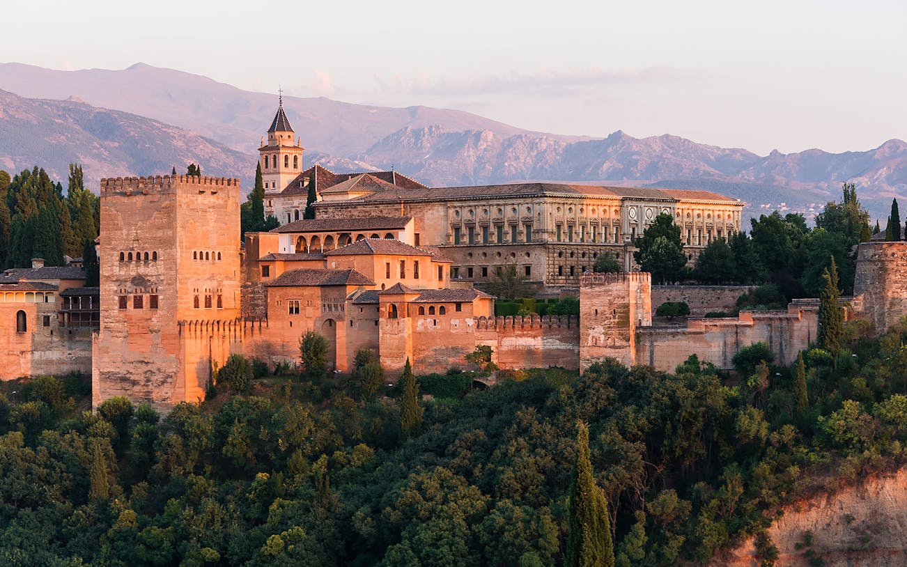 Alhambra Palace and Generalife gardens in Granada, Spain, with mountainous backdrop.