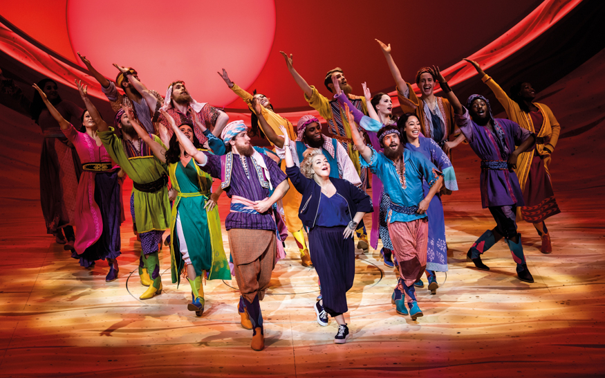 Performers in colorful costumes on stage during a "Joseph" musical production.