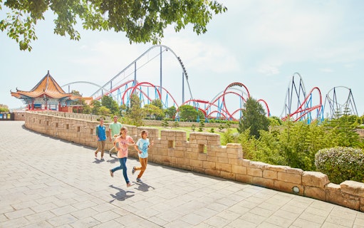 Visitors walking near roller coasters at PortAventura Park, Spain.