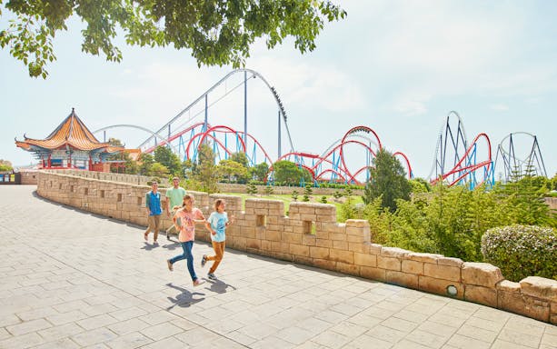 Visitors walking near roller coasters at PortAventura Park, Spain.