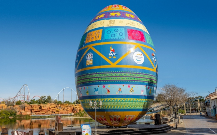 Decorative egg sculpture at PortAventura Park with roller coaster in background.