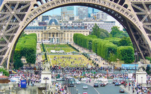 View of Champ de Mars from Eiffel Tower, Paris, with crowds and cityscape in the background.