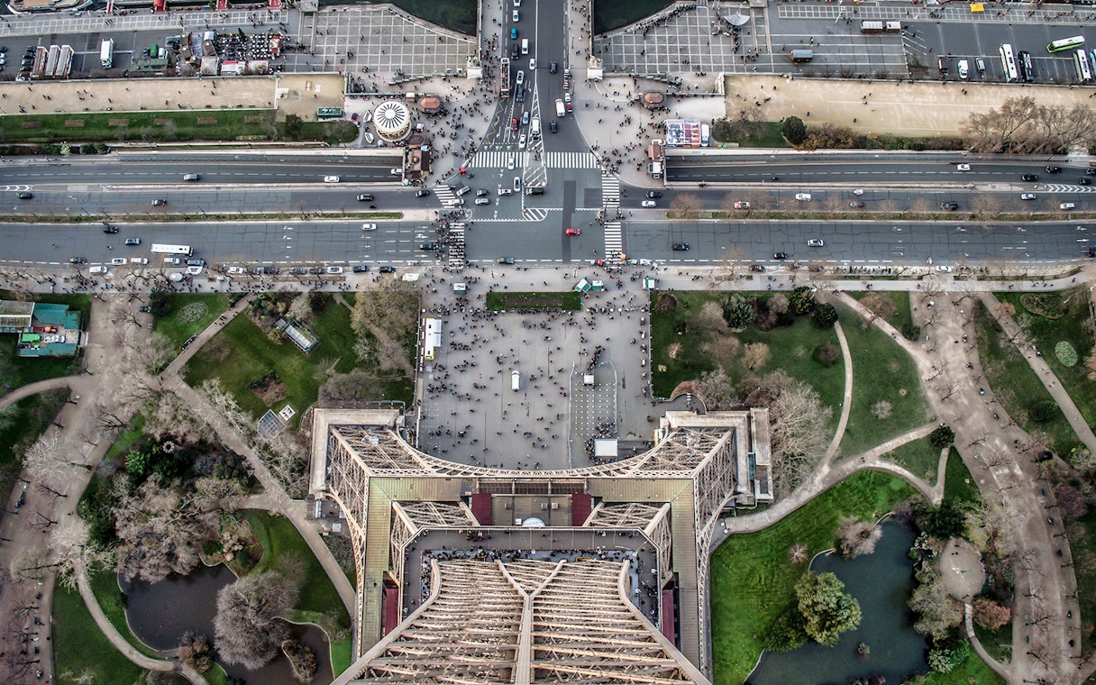 Aerial view from Eiffel Tower summit overlooking Paris streets and gardens.