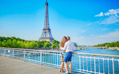 Couple enjoying view of Eiffel Tower from Seine River bridge, Paris.