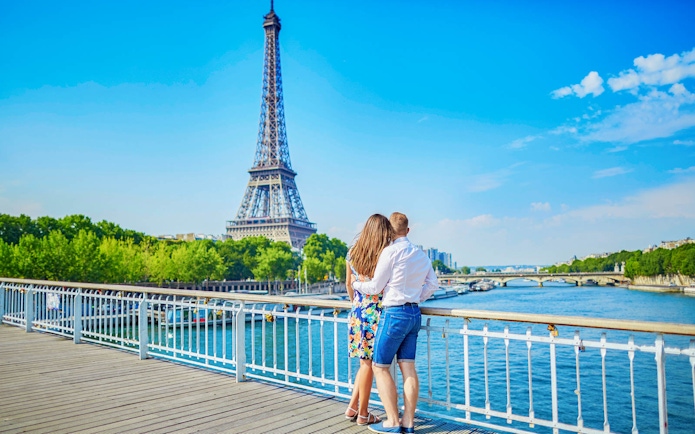 Couple enjoying view of Eiffel Tower from Seine River bridge, Paris.