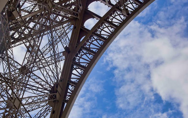 Eiffel Tower iron lattice detail against blue sky, Paris.
