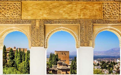 Alhambra arches overlooking Granada cityscape and mountains.