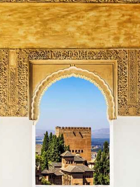Alhambra arches overlooking Granada cityscape and mountains.