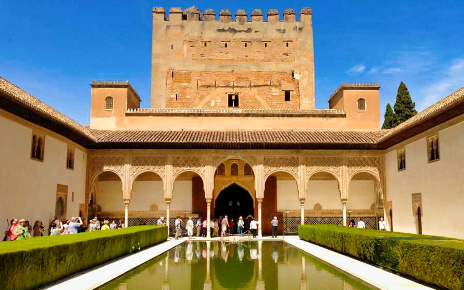 Alhambra courtyard with reflecting pool and visitors, Granada, Spain.
