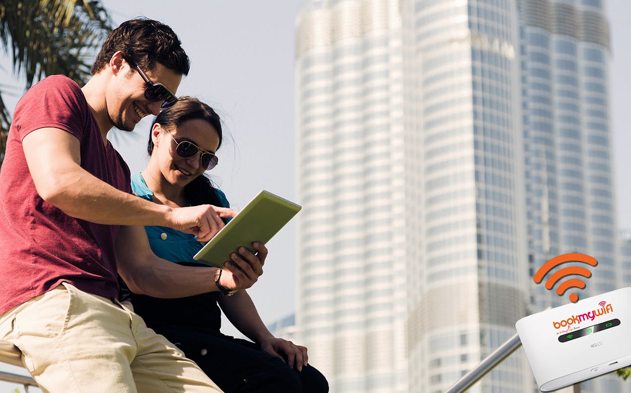 Couple using tablet with pocket WiFi rental in front of Burj Khalifa, Dubai.