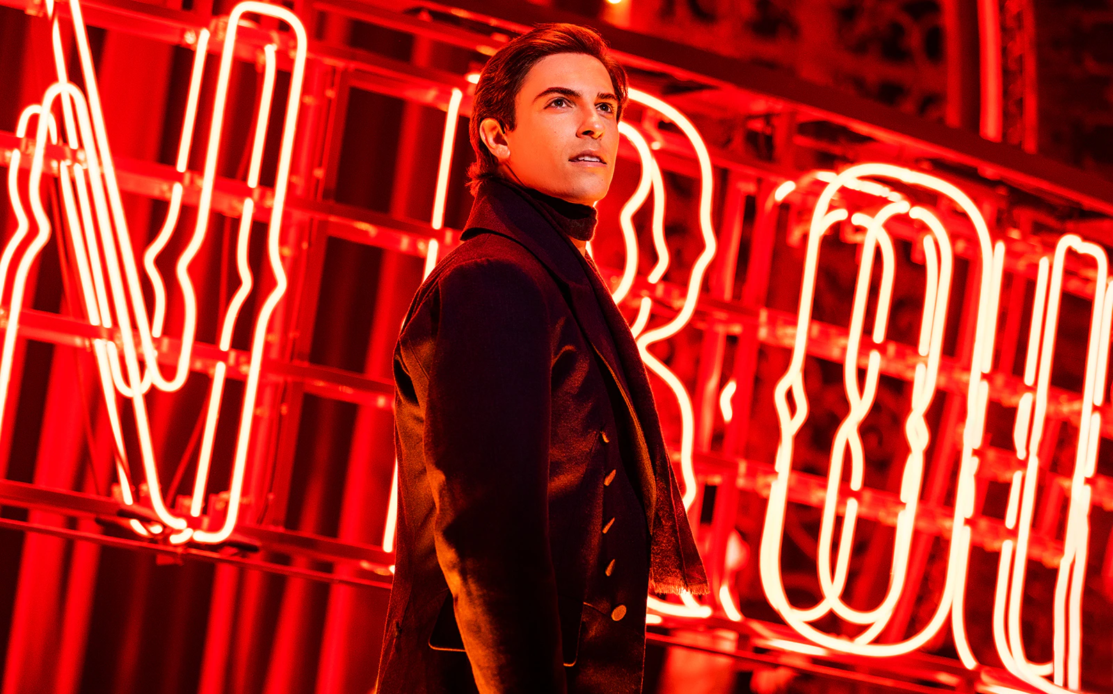 Performer in front of Moulin Rouge neon sign during the musical.