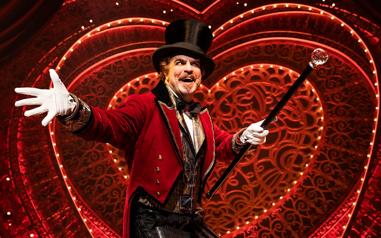 Performer in red coat and top hat on stage at Moulin Rouge! The Musical.