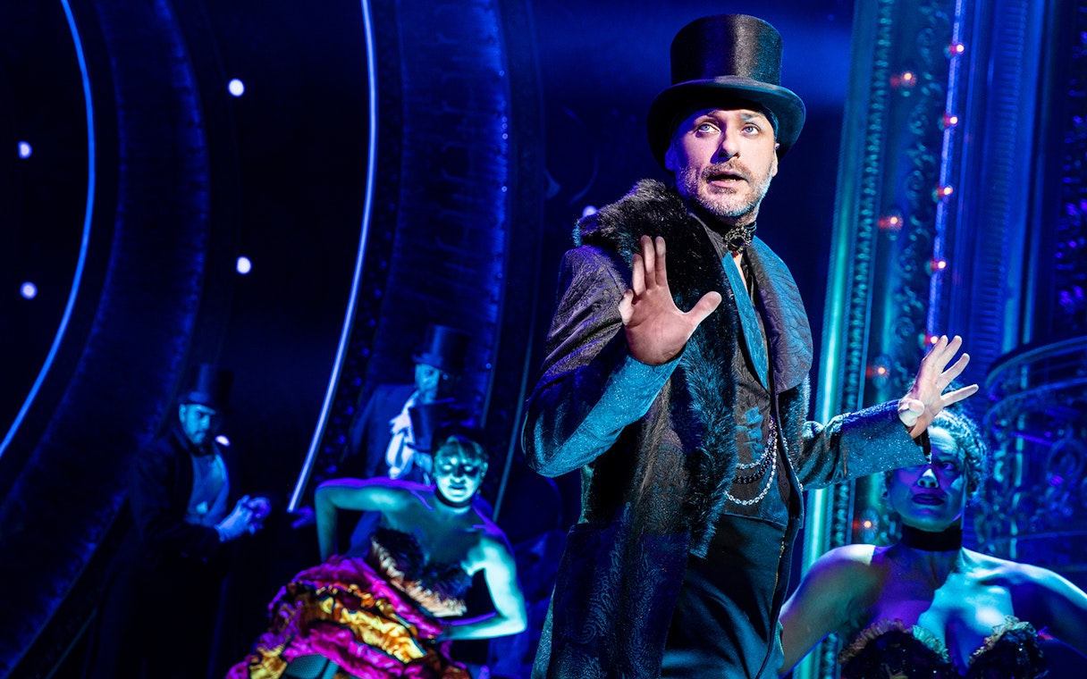 Performer in top hat on stage during Moulin Rouge! The Musical.