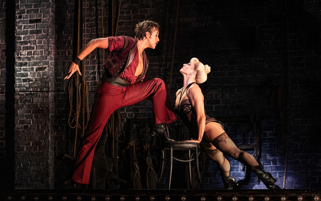 Performers in a dramatic scene from Moulin Rouge! The Musical on stage.