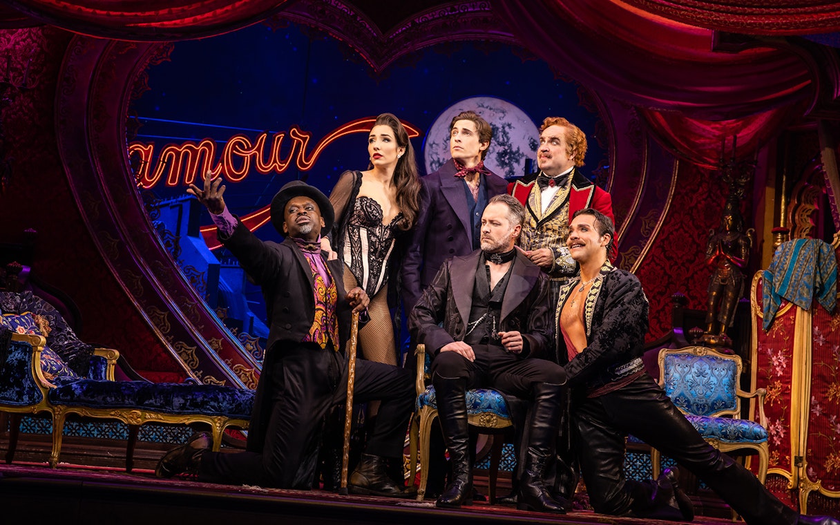 Cast of Moulin Rouge! The Musical on stage with vibrant set design.