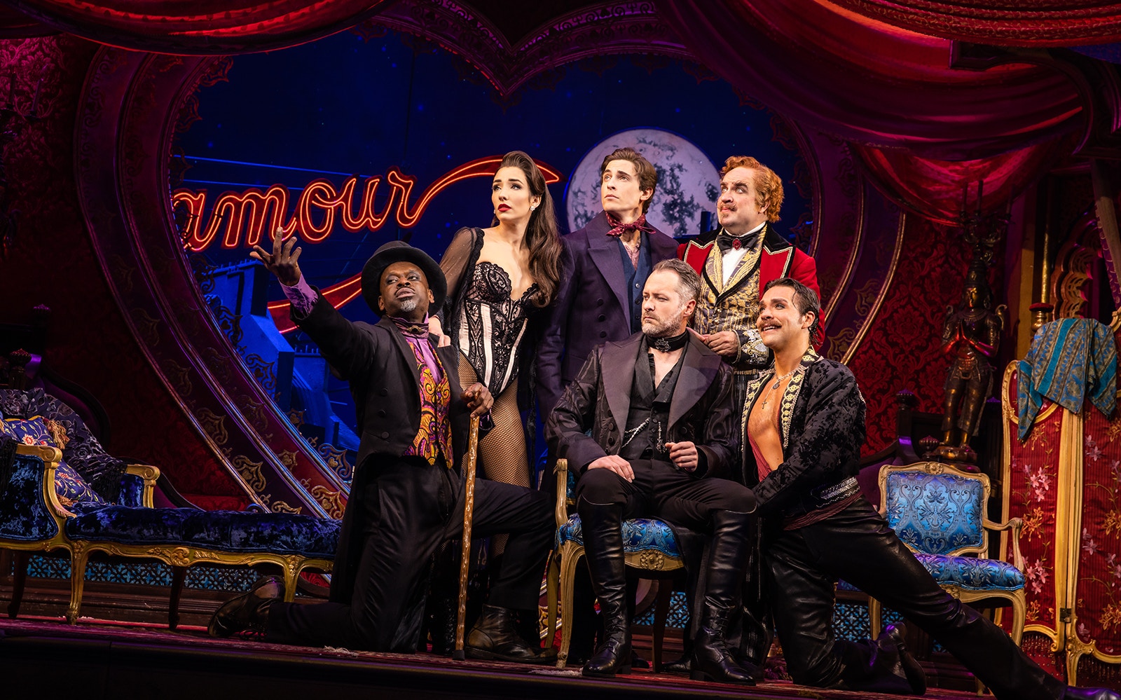 Cast of Moulin Rouge! The Musical on stage with vibrant set design.