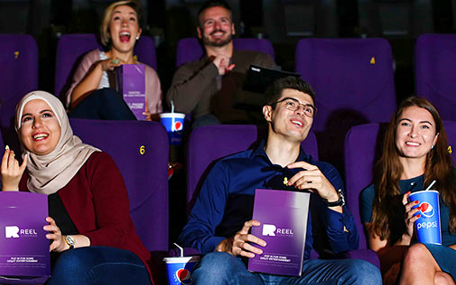 People enjoying a movie at Dubai Mall cinema with snacks and drinks.