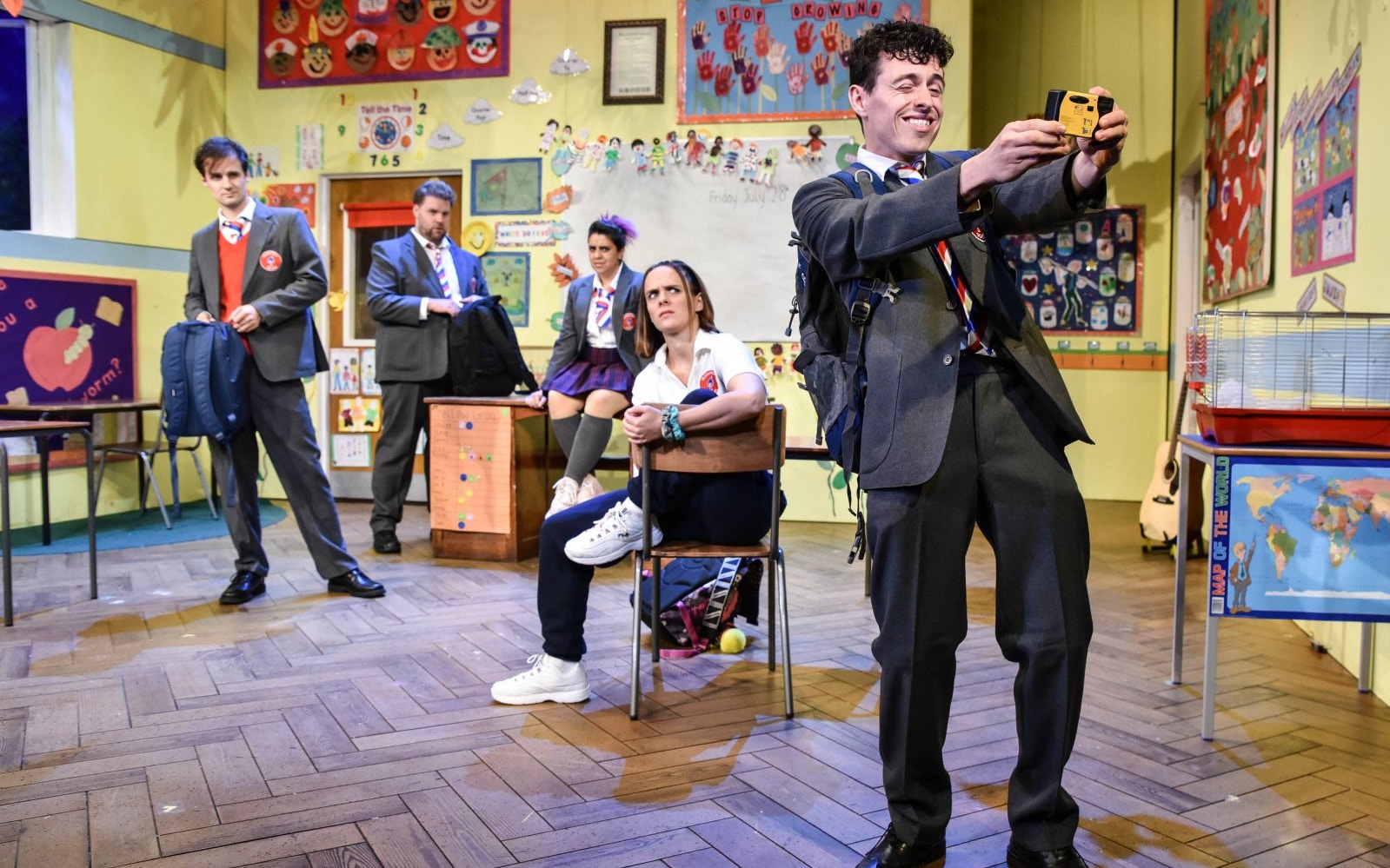 Actors in a classroom setting from the play "Groan Ups" performing a scene.