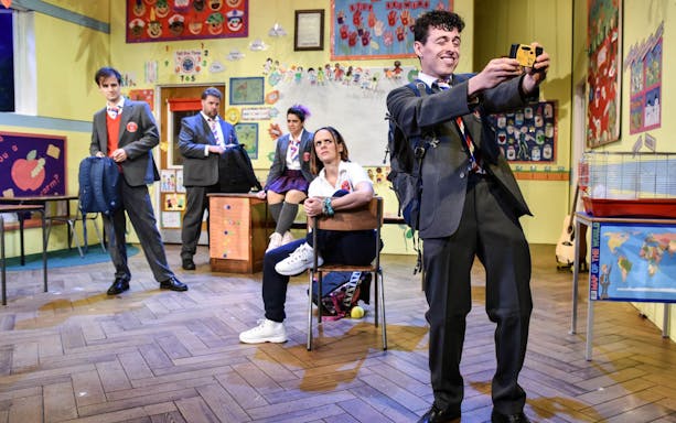 Actors in a classroom setting from the play "Groan Ups" performing a scene.