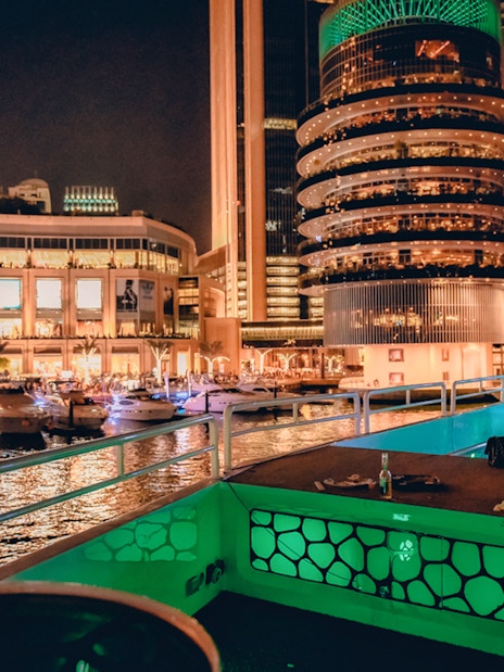 Mega yacht deck with dining setup, Dubai Marina skyline at night.