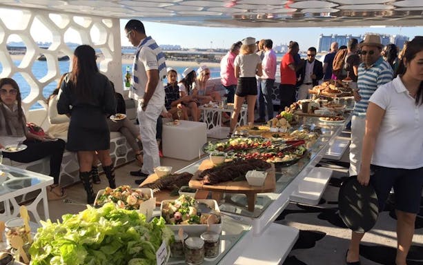 Guests enjoying a buffet on a Mega Yacht Dinner Cruise by Westin with city views.
