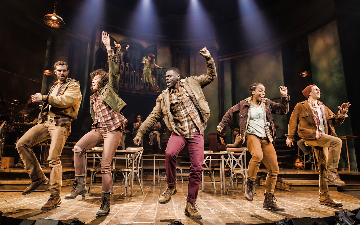 Performers dancing energetically on stage during Hadestown musical.