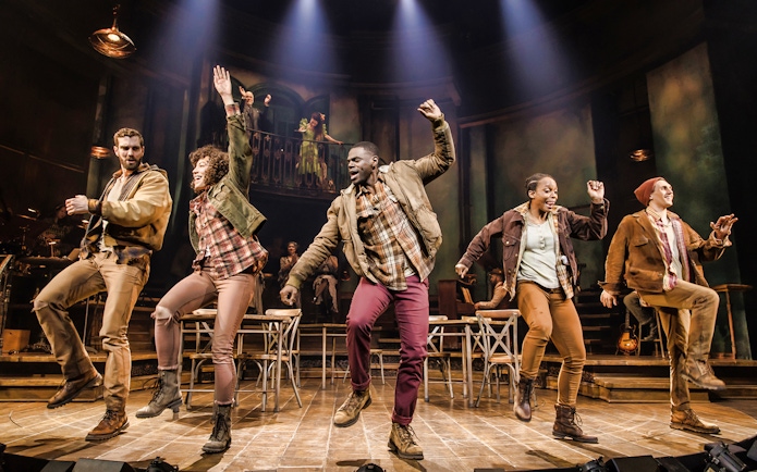 Performers dancing energetically on stage during Hadestown musical.