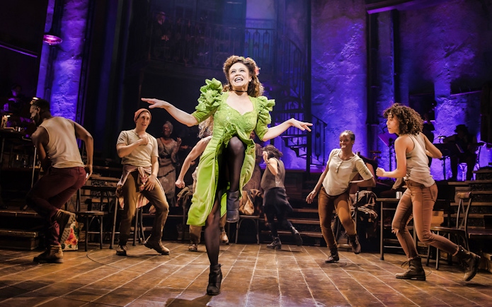 Performers dancing energetically on stage during Hadestown musical.