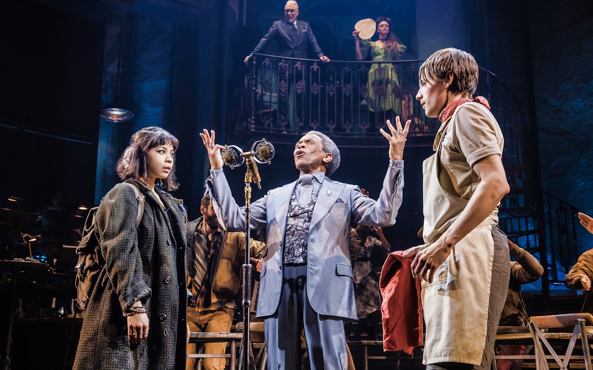 Actors performing a scene from the musical Hadestown on stage.