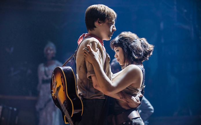 Performers embrace on stage during Hadestown musical.