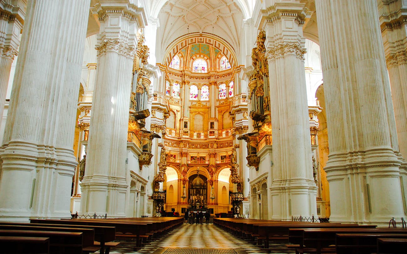 Granada Cathedral interior with ornate columns and stained glass windows.