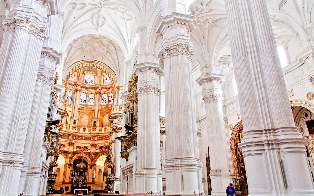 Granada Cathedral interior with ornate columns and stained glass windows.