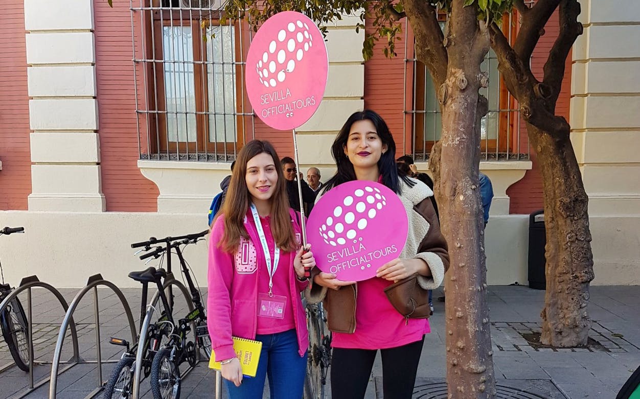Sevilla Official Tours guides holding signs for Giralda and Cathedral tour.