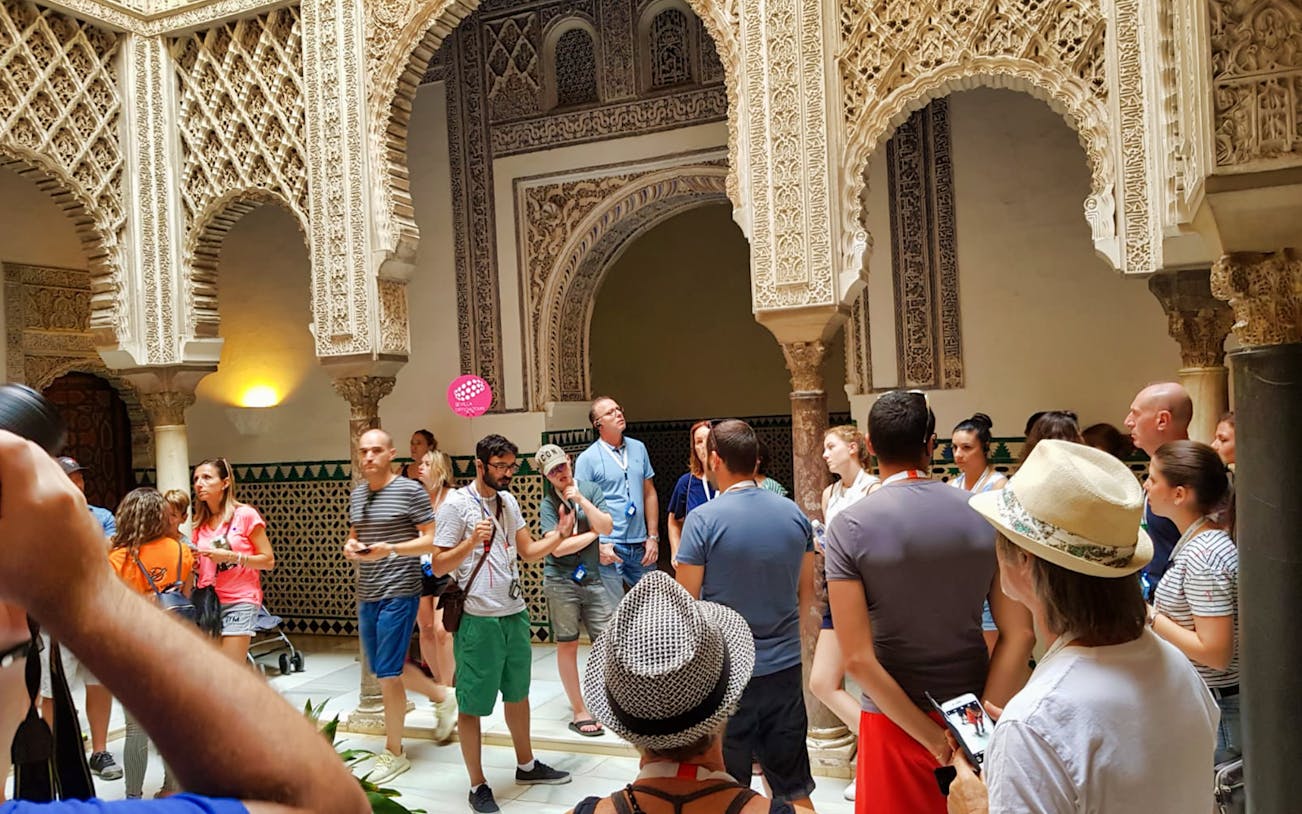 Tour group exploring ornate arches in Seville's Giralda and Cathedral.