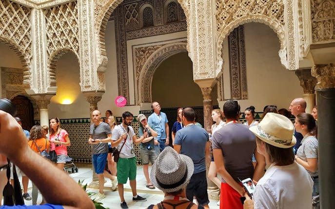 Tour group exploring ornate arches in Seville's Giralda and Cathedral.
