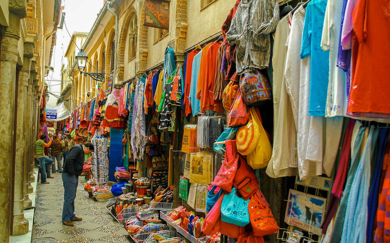 Granada street market with colorful clothes and souvenirs on a tapas walking tour.