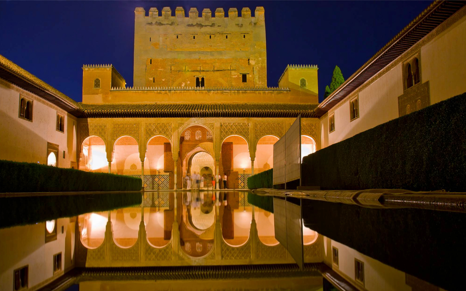 Alhambra's Nasrid Palaces reflecting in a courtyard pool at night, Granada, Spain.
