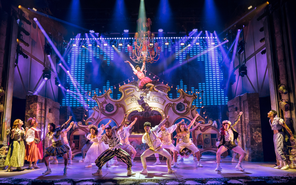 Performers on stage during &Juliet musical, vibrant choreography under a chandelier.