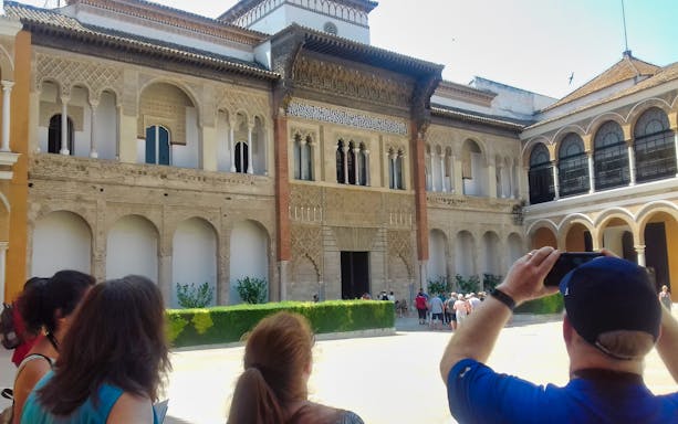 Tourists exploring the courtyard of the Alcázar in Seville.