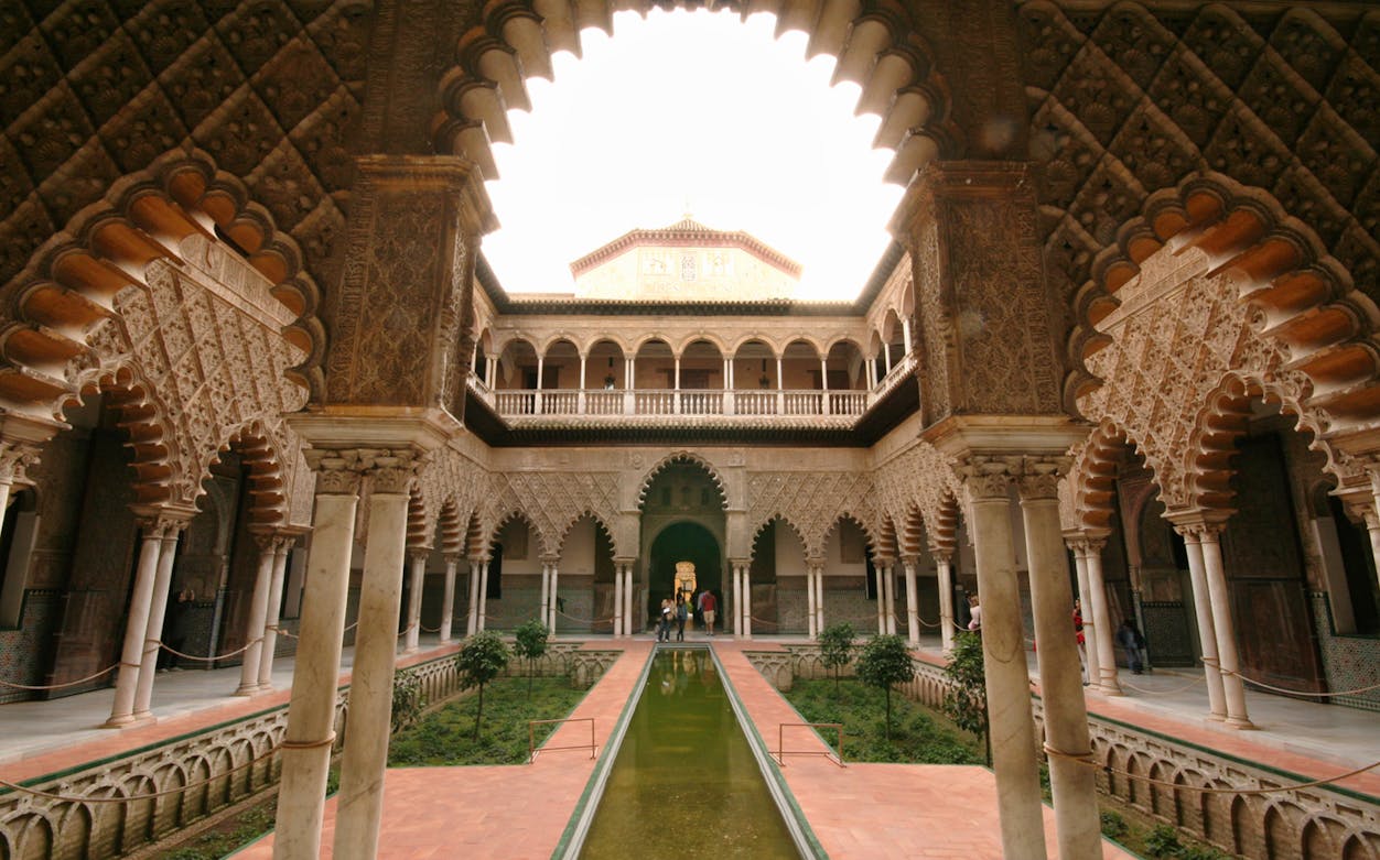 Real Alcazar courtyard with intricate arches and reflecting pool, Seville.