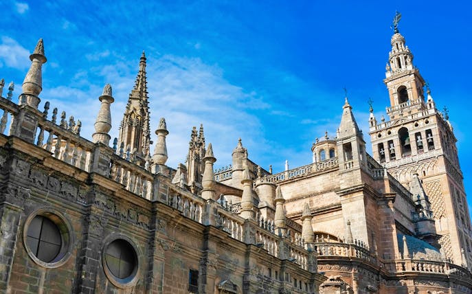 Seville Cathedral and Giralda tower under a clear blue sky.