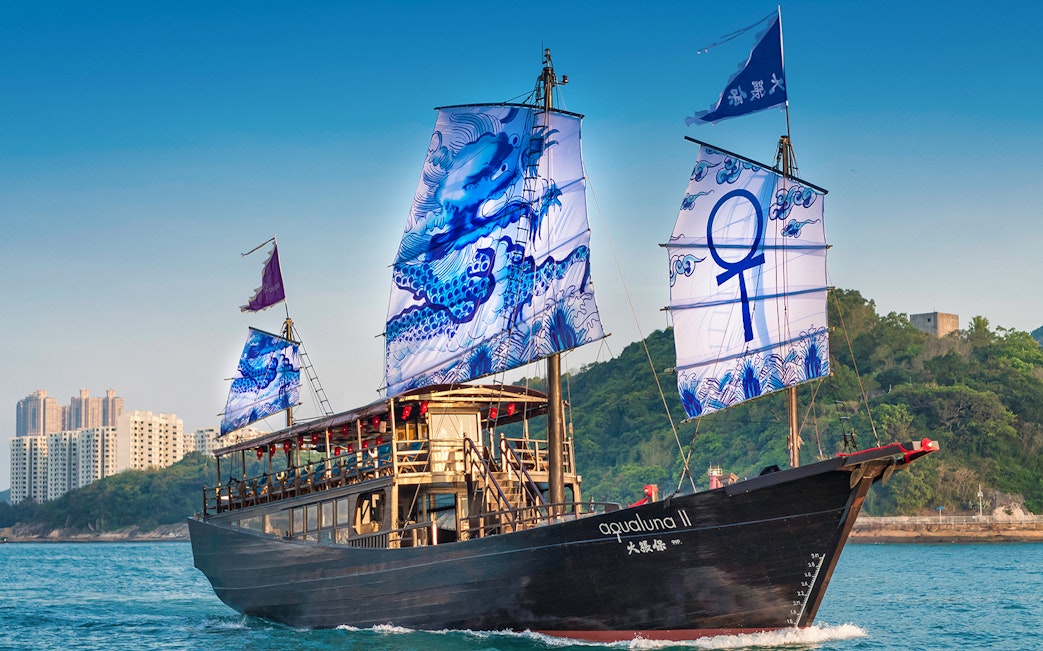 AquaLuna junk boat sailing near Stanley, Hong Kong with blue dragon sails.