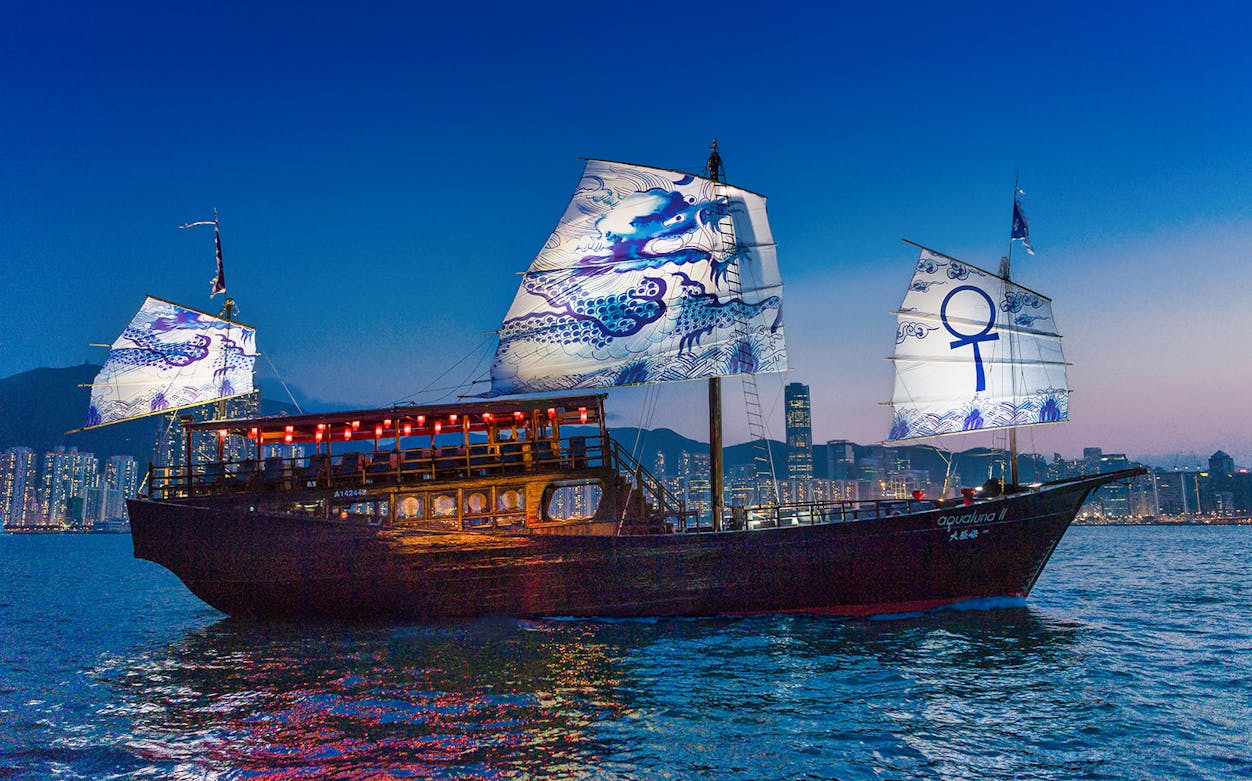 Traditional junk boat with illuminated sails on Hong Kong's Victoria Harbour during Aquluna Harbour Discovery Tour.