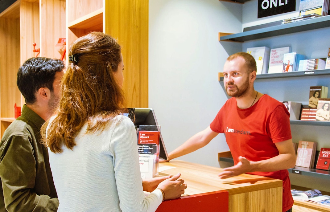 Turistas en el mostrador de información de I amsterdam