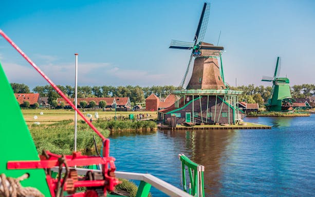Windmills at Zaanse Schans near water, part of Amsterdam City Tour.