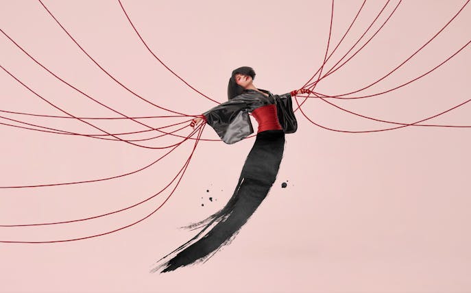 Performer in traditional attire with red cords, inspired by Madama Butterfly.