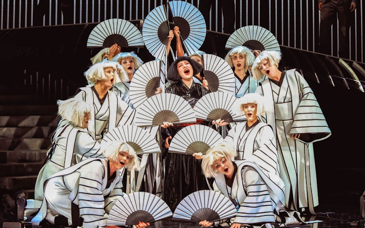 Performers in traditional costumes with fans in a scene from Madama Butterfly.