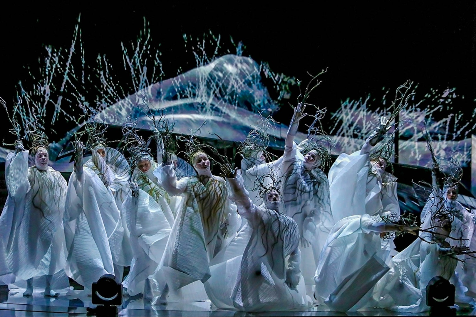 Performers in white costumes with branches in Madama Butterfly opera scene.