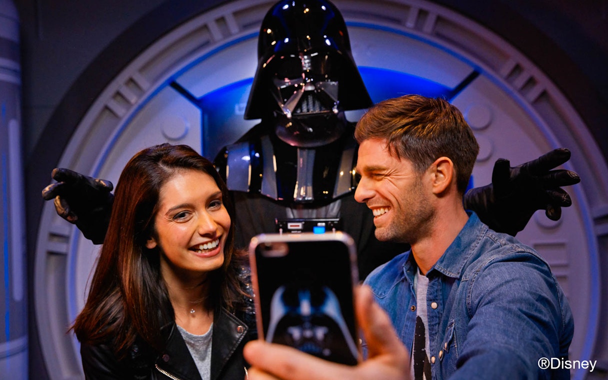Visitors taking a selfie with a character at Disney Park.