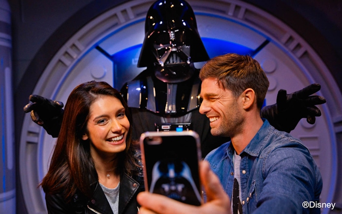 Visitors taking a selfie with a character at Disney Park.